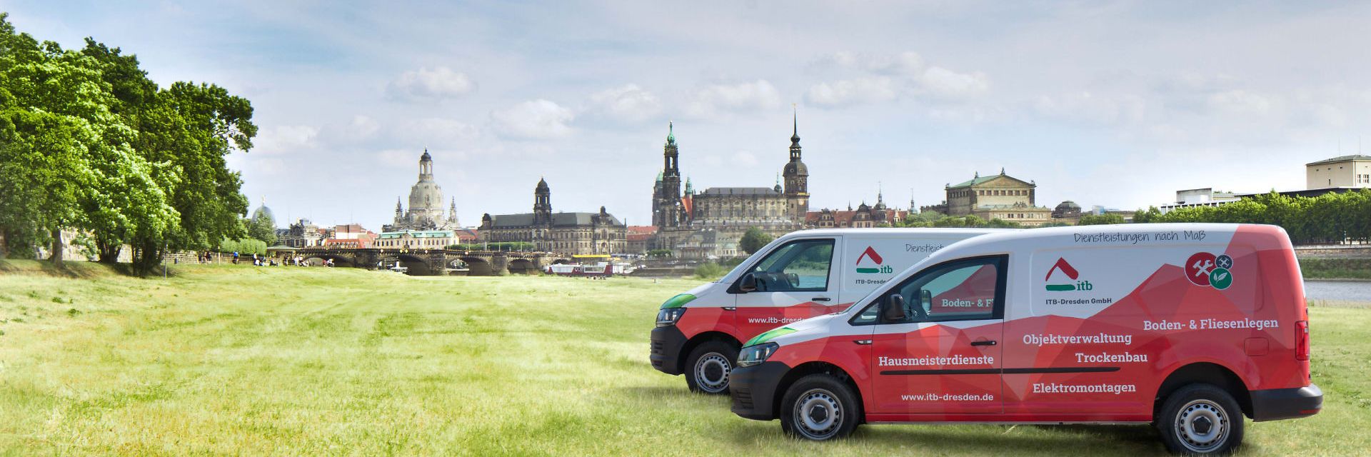 Zwei Firmenfahrzeuge auf den Elbwiesen, im Hintergrund die Skyline von Dresden