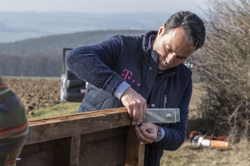 Telekom Techniker schraubt Winkel an Holzbalken