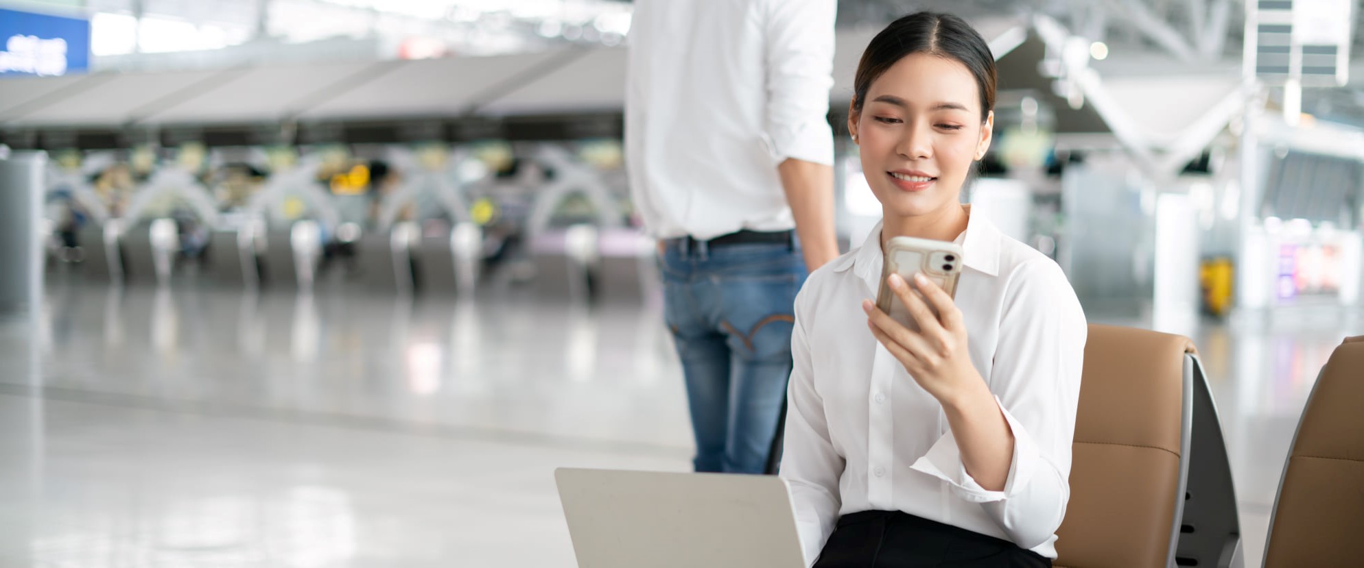 Frau am Flughafen nutzt mobiles Internet