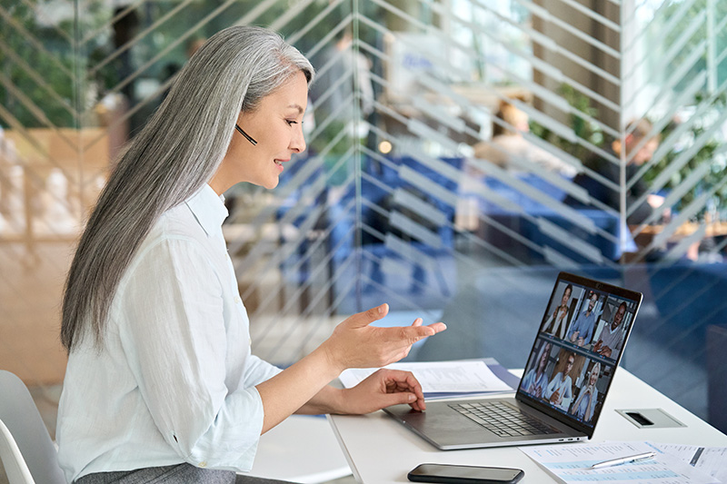 Frau mit Headset vor Laptop in Online-Meeting