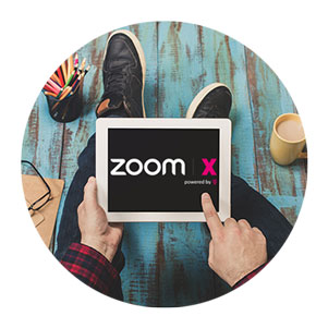 Hände halten ein Tablet mit Zoom Logo auf dem Bildschirm
