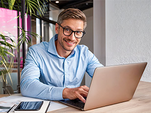 Ein Mann in blauem Hemd arbeitet am Laptop