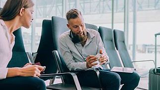 Frau und Mann am Flughafen mit Smartphone in der Hand