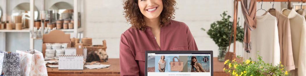 Frau Präsentiert in Ihrem Laden auf einem Laptop ihren neuen mit der Telekom erstellten Webshop.