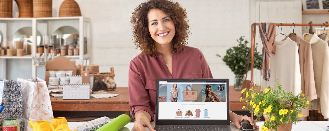 Frau Präsentiert in Ihrem Laden auf einem Laptop ihren neuen mit der Telekom erstellten Webshop.