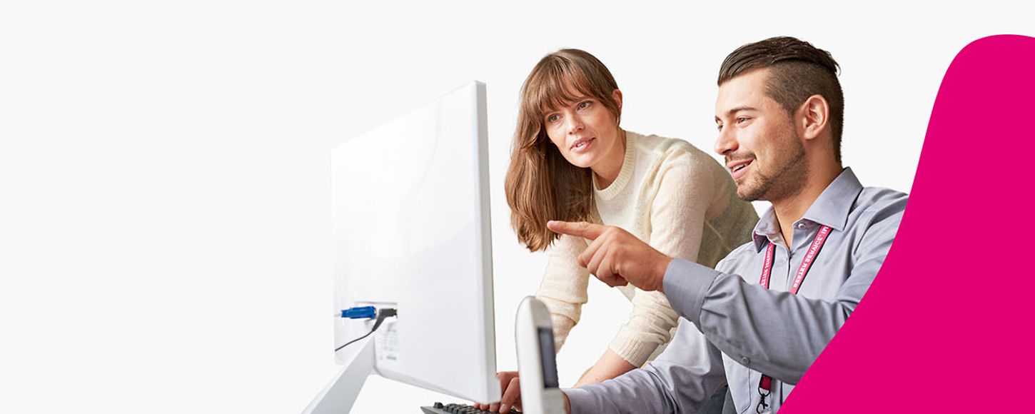 Ein Mann und eine Frau im Gespräch vor einem Apple Monitor