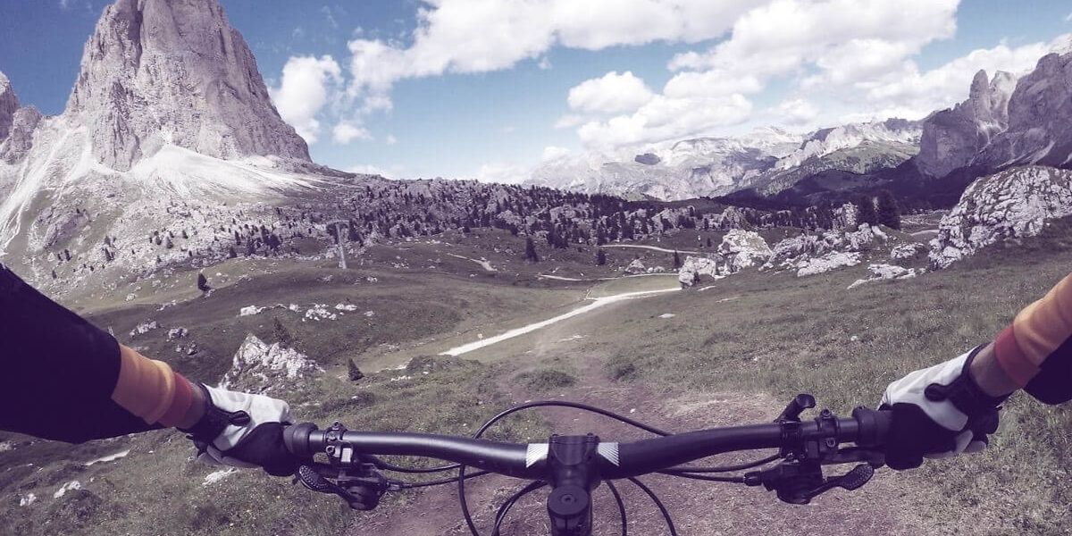 Mountainbike aus Fahrer*innen-Sicht vor sommerlicher Bergkulisse