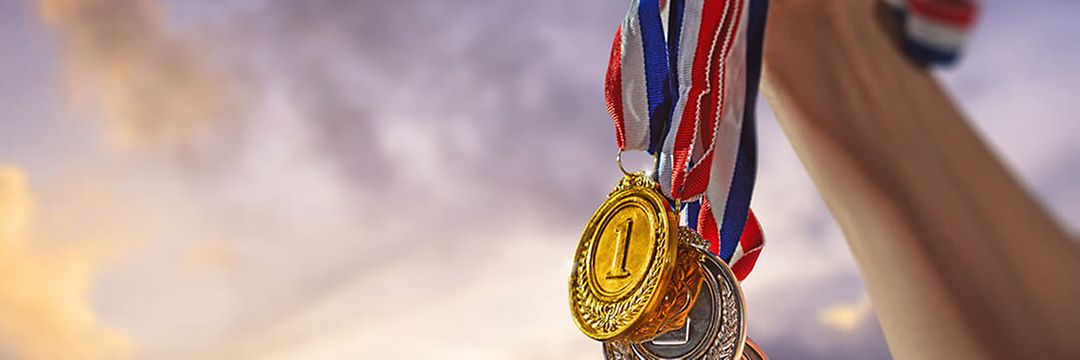 Drei Medaillen werden in die Luft gehalten