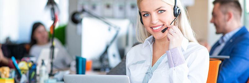 Junge Frau mit Headset im Büro vor PC