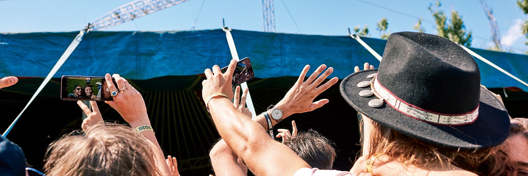 Viele junge Menschen strecken Ihre Handy in die Luft und sind vermutlich auf einem Open Air Konzert.