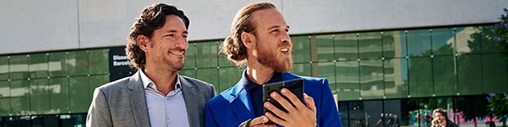 Zwei Männer unterwegs lachend mit Smartphone 