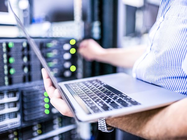 Man holding laptop and working on a server cabinet