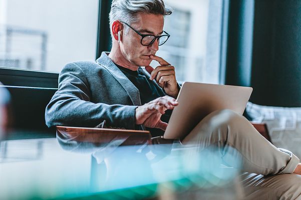 Geschäftsmann vertieft sich in digitale Fachinhalte am Laptop – Know-how & Insights von T Business