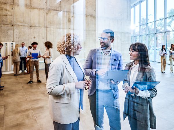 Team von lächelnden Unternehmern, die sich in einem Flur beraten.