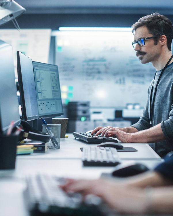 Portrait of a thoughtful engineer working on a desktop computer in a technological office environment.