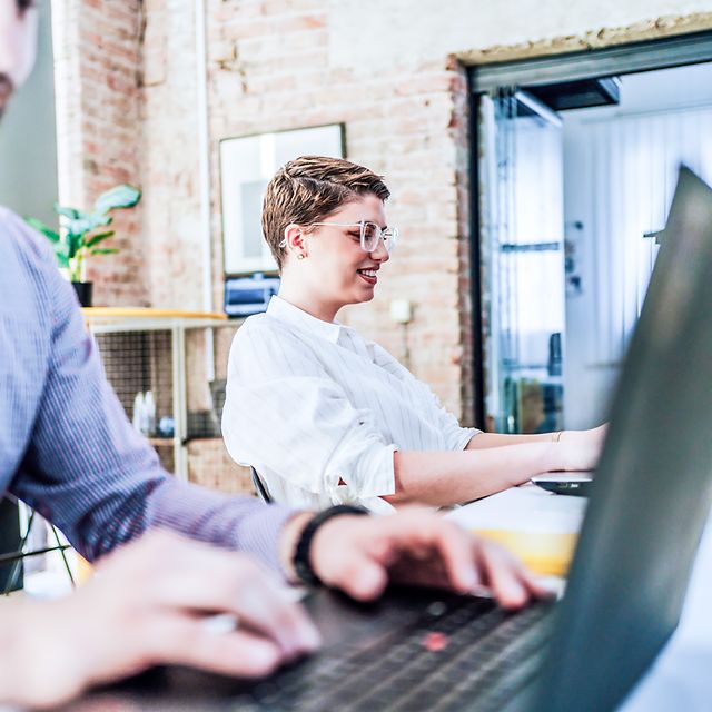 Two people working on laptops in an office