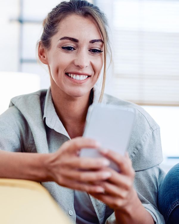 A young woman looks at her smartphone with a smile: as a Cloud Solution Partner, she has complete flexibility.