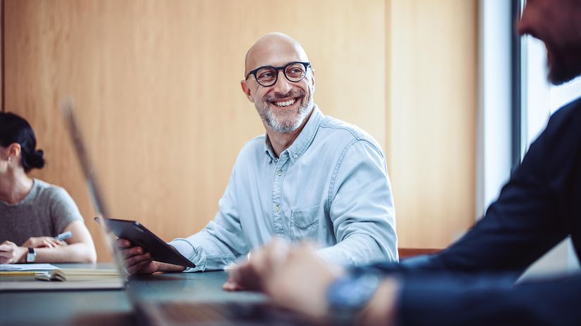 Smiling man with glasses using phone for Microsoft Teams X
