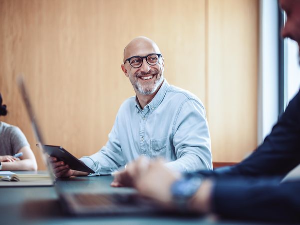 Smiling man with glasses using phone for Microsoft Teams X