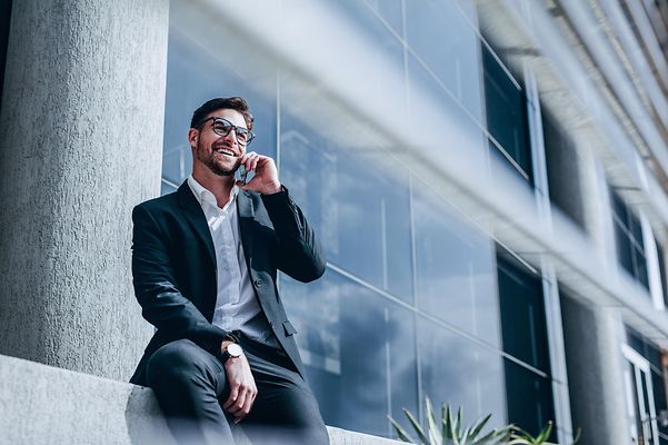 A smiling businessman makes a phone call using Microsoft Teams telephony.