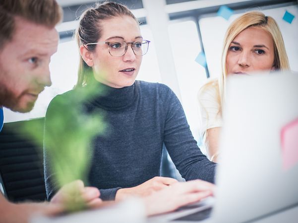 A group of colleagues looking at a notebook together