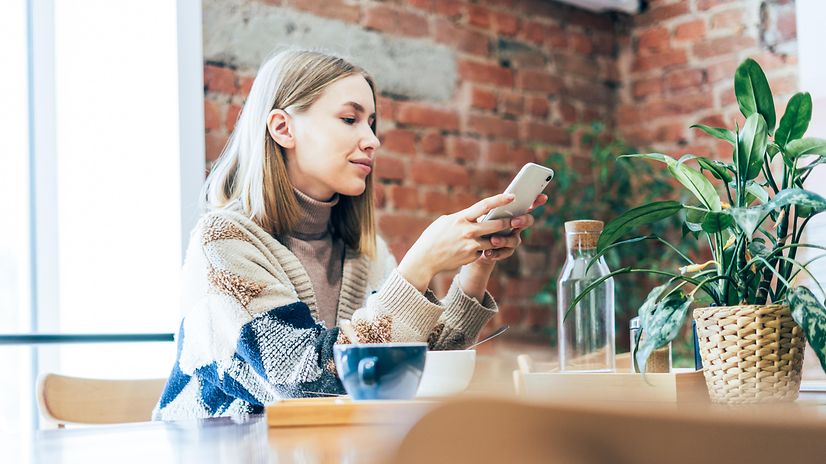 A young woman works from home at the breakfast table.