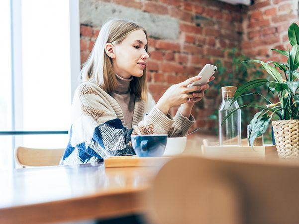 A young woman works from home at the breakfast table.