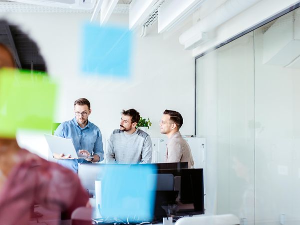 Colleagues develop strategies on their laptops using Microsoft Copilot