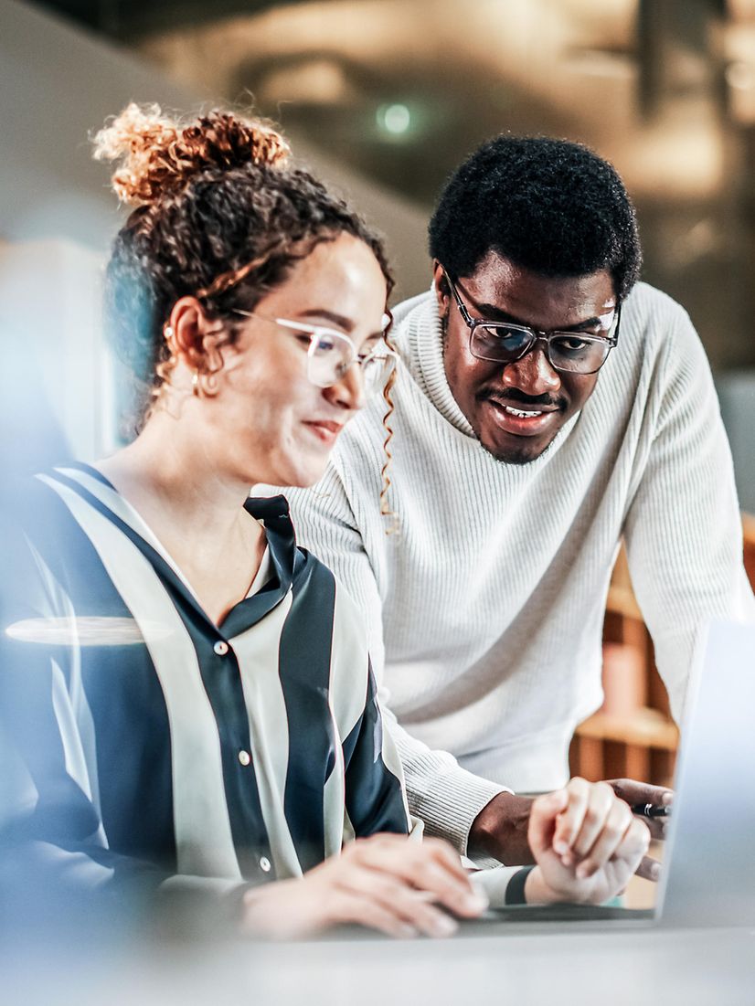 Portrait of two creative colleagues using a laptop to discuss a work project in the office.