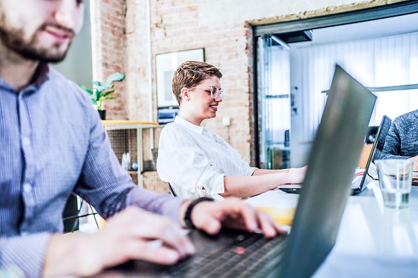 Colleagues sit smiling in the office while following a Zoom X webinar.