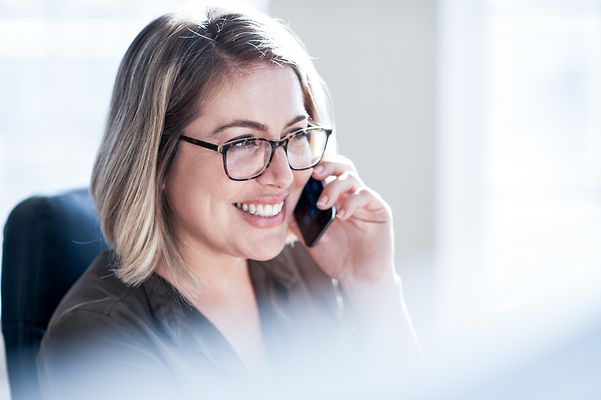 Photograph of a young businesswoman talking on a mobile phone in an office