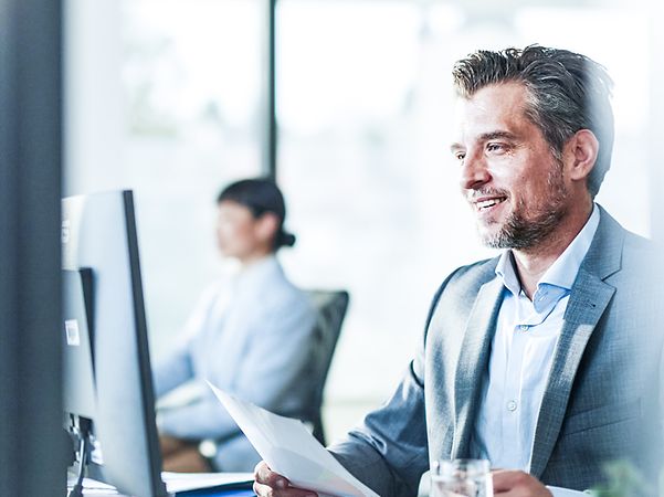 Man in office sitting in front of a computer using Zoom X.