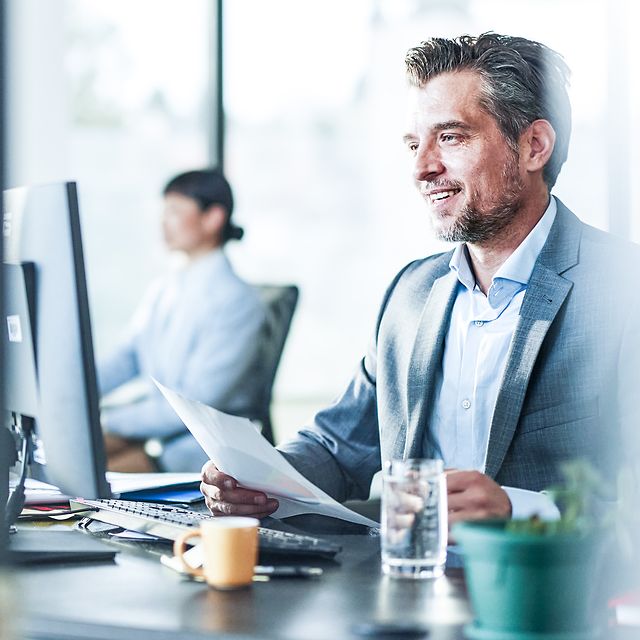 Man in office sitting in front of a computer using Zoom X.