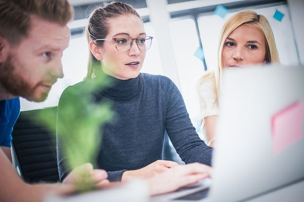 A group of colleagues looking at a notebook together