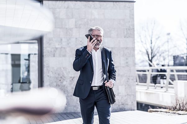 A businessman makes a phone call outside a modern building.