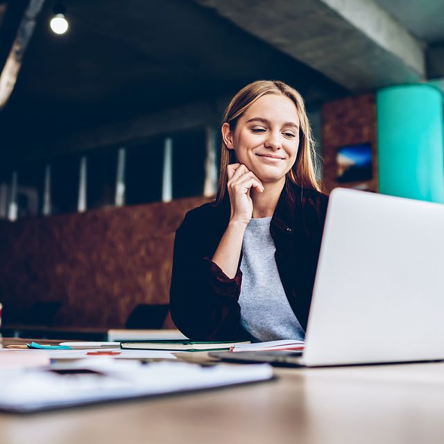 Young woman has successfully used DocuSign and is sitting smiling in front of her laptop.