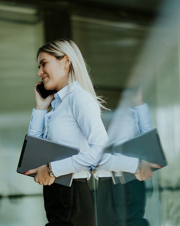 A woman with a mobile phone and tablet receives a notification via DocuSign.
