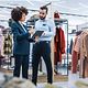 A woman and a man are standing in a clothing shop, approving a business transaction on a tablet using DocuSign.