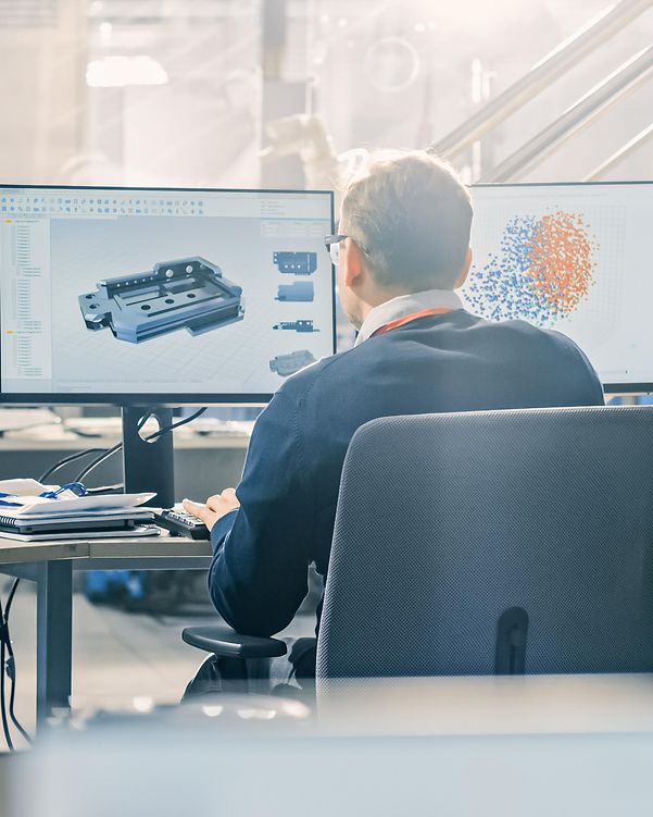 A man working on a computer with two monitors