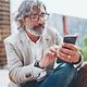 An elderly gentleman glances at his smartphone.