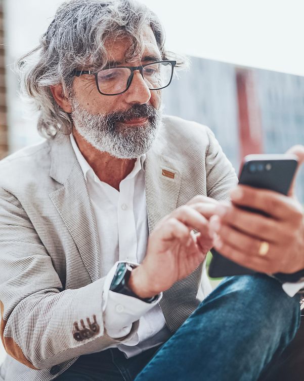 An elderly gentleman glances at his smartphone.