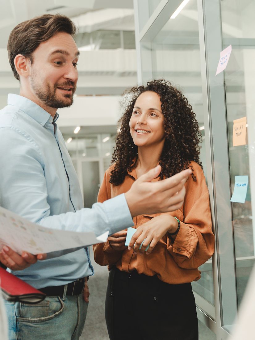 Several people are working together in an open-plan office and talking about Hubdrive.