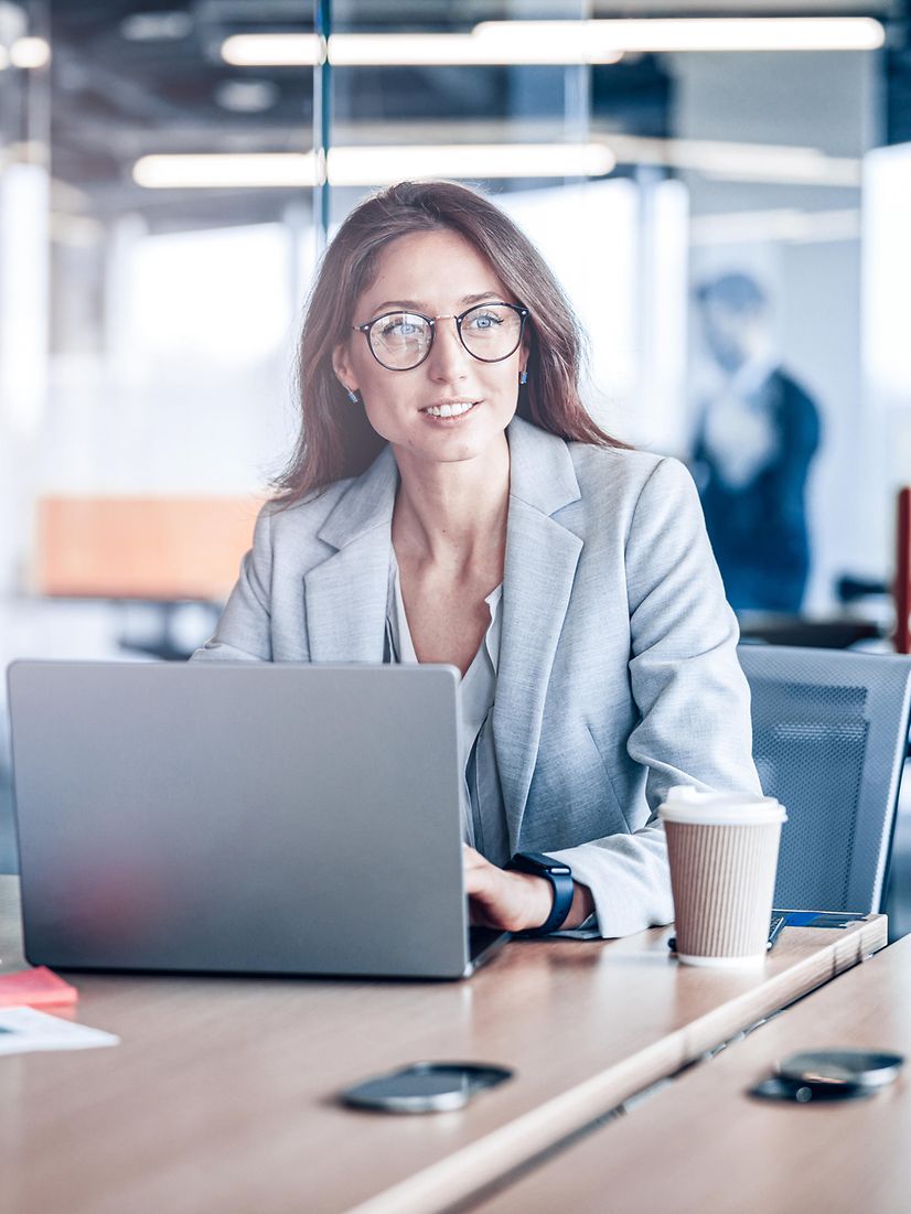 A woman works on her laptop in a modern office on the topic of Salesforce Energy & Utilities Cloud.
