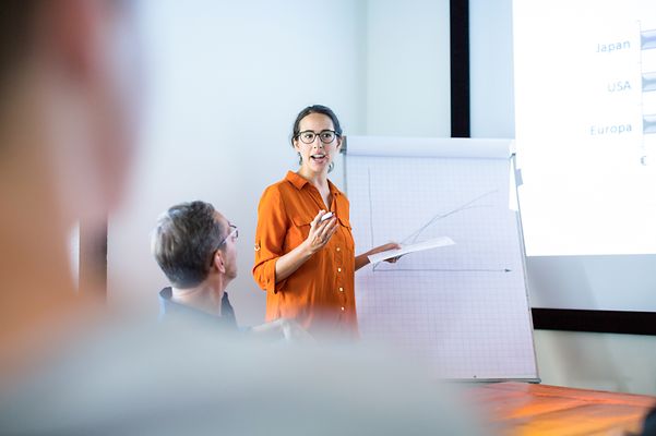 A female manager presents personnel statistics to her superiors.