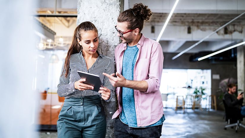 Two people with tablets discuss Telekom's SAP solutions for small and medium-sized businesses in a modern office.