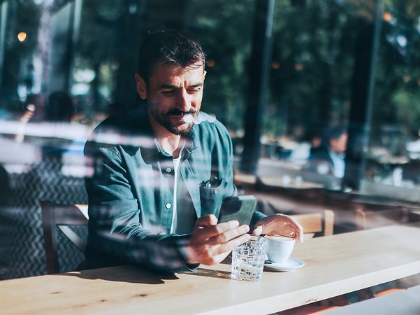 A man in a café reads a message that was sent via mass text messaging.