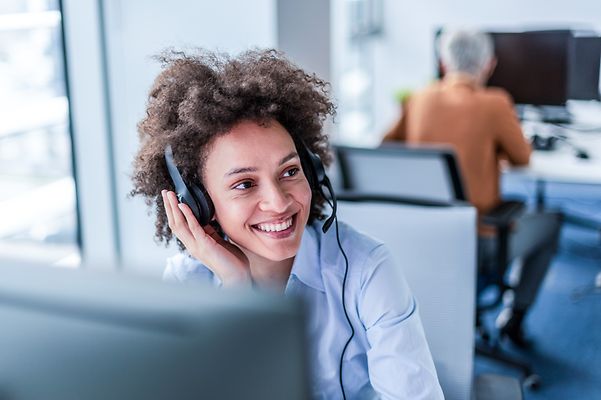 Customer service representative speaking on a headset in the office.