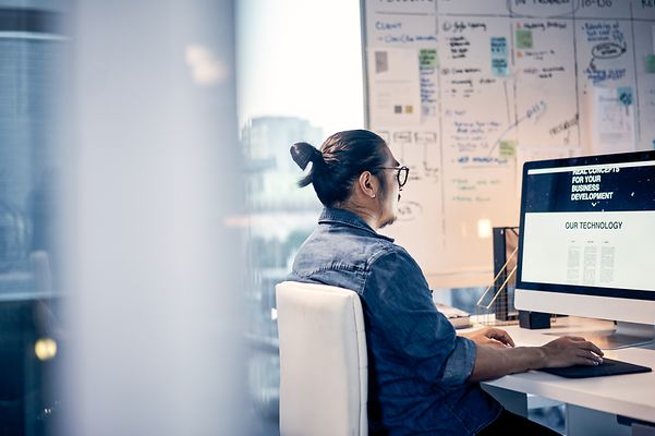 A man in an office researches Telekom's managed service portfolio for networking on his desktop PC.
