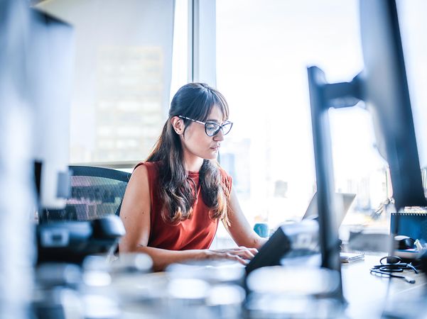 A woman sits at a laptop in a bright office and learns about the features of Microsoft Azure.