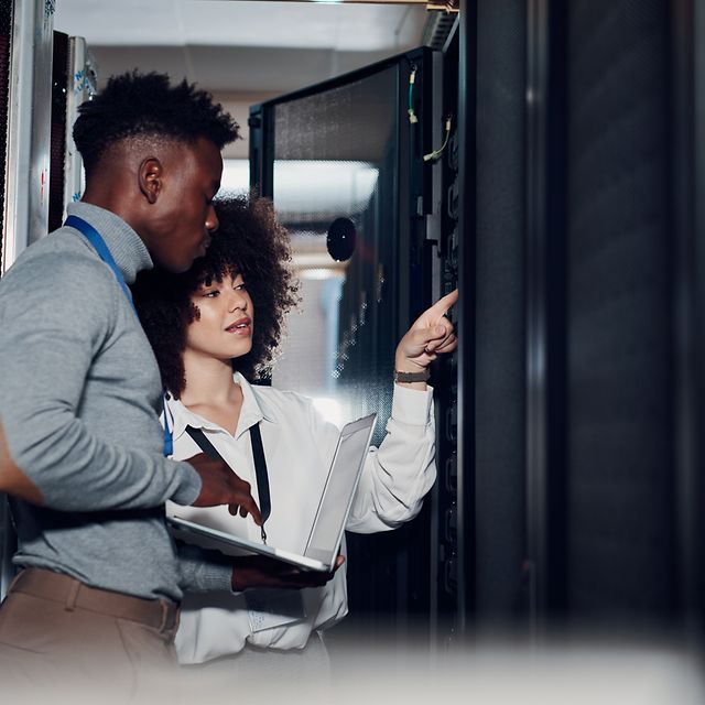 Two people inspect a Telekom server cabinet.